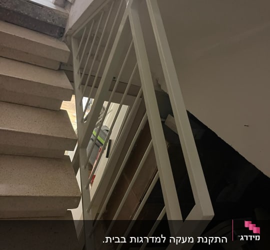 מעקה מתכת לבן במדרגות פנימיות